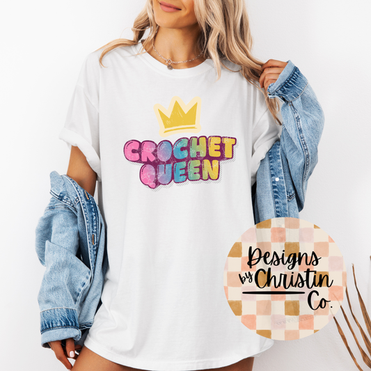 Person wearing a white t-shirt with 'Crochet Queen' text and a crown graphic, holding a denim jacket.