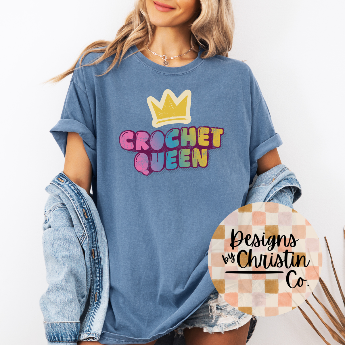 Person wearing a blue t-shirt with 'Crochet Queen' text and a crown graphic, with a denim jacket and shorts.