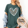 Person wearing a green t-shirt with a colorful heart design, standing against a white background.