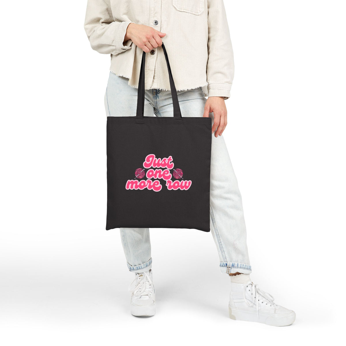 Person holding a black tote bag with pink text on a white background