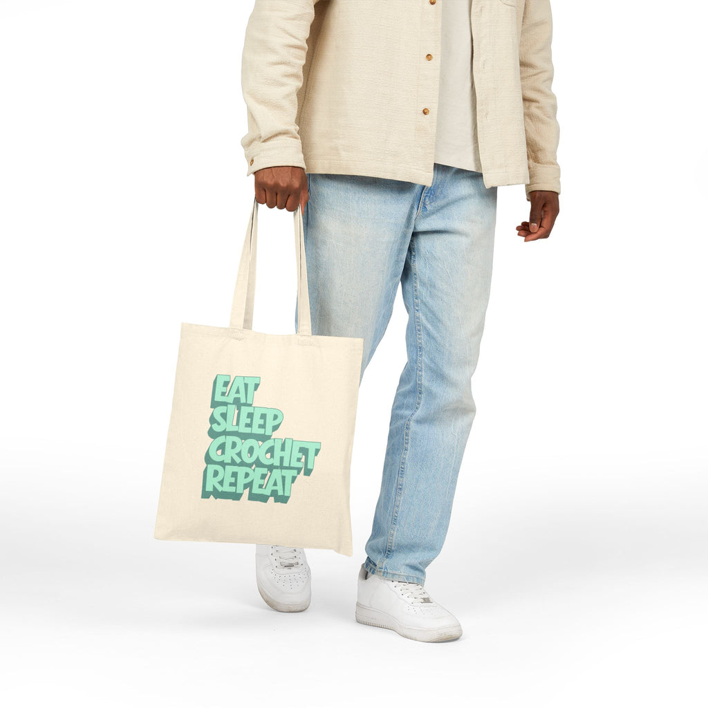 Person holding a tote bag with 'Eat Sleep Crochet Repeat' text on a white background