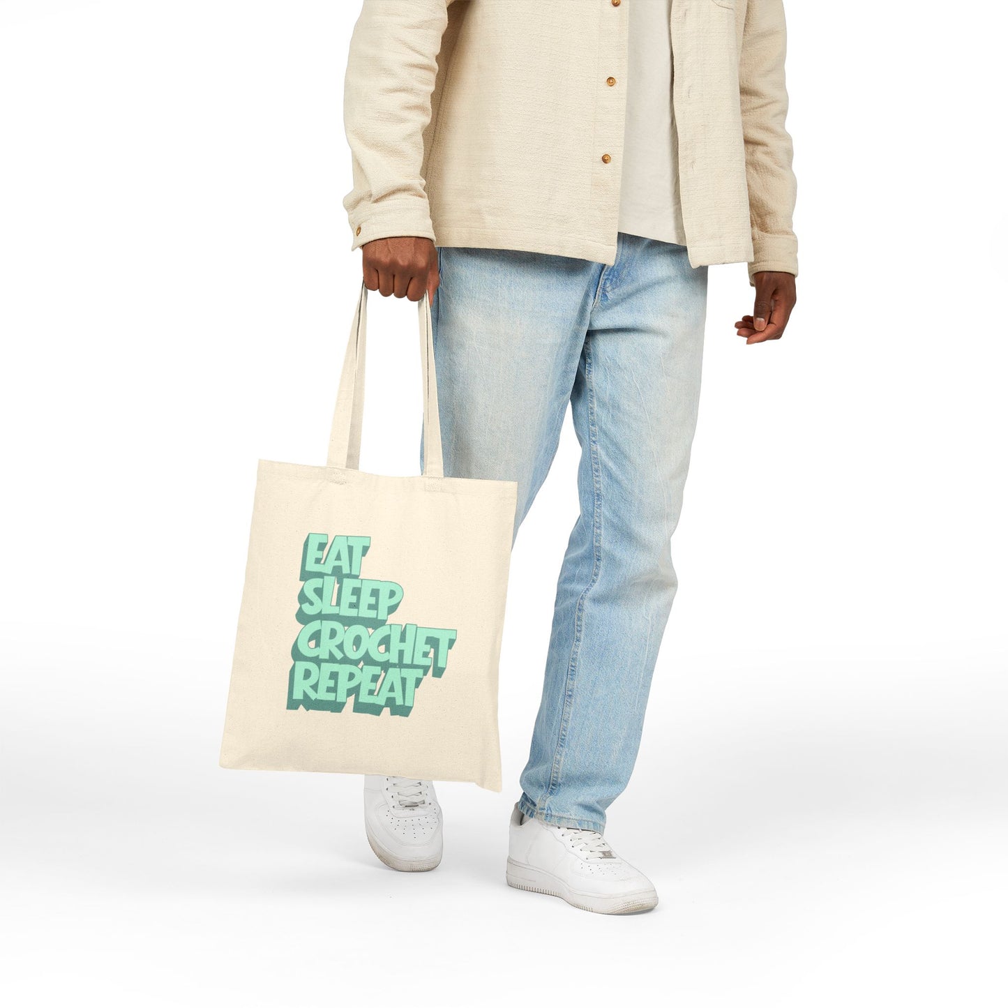 Person holding a tote bag with 'Eat Sleep Crochet Repeat' text on a white background