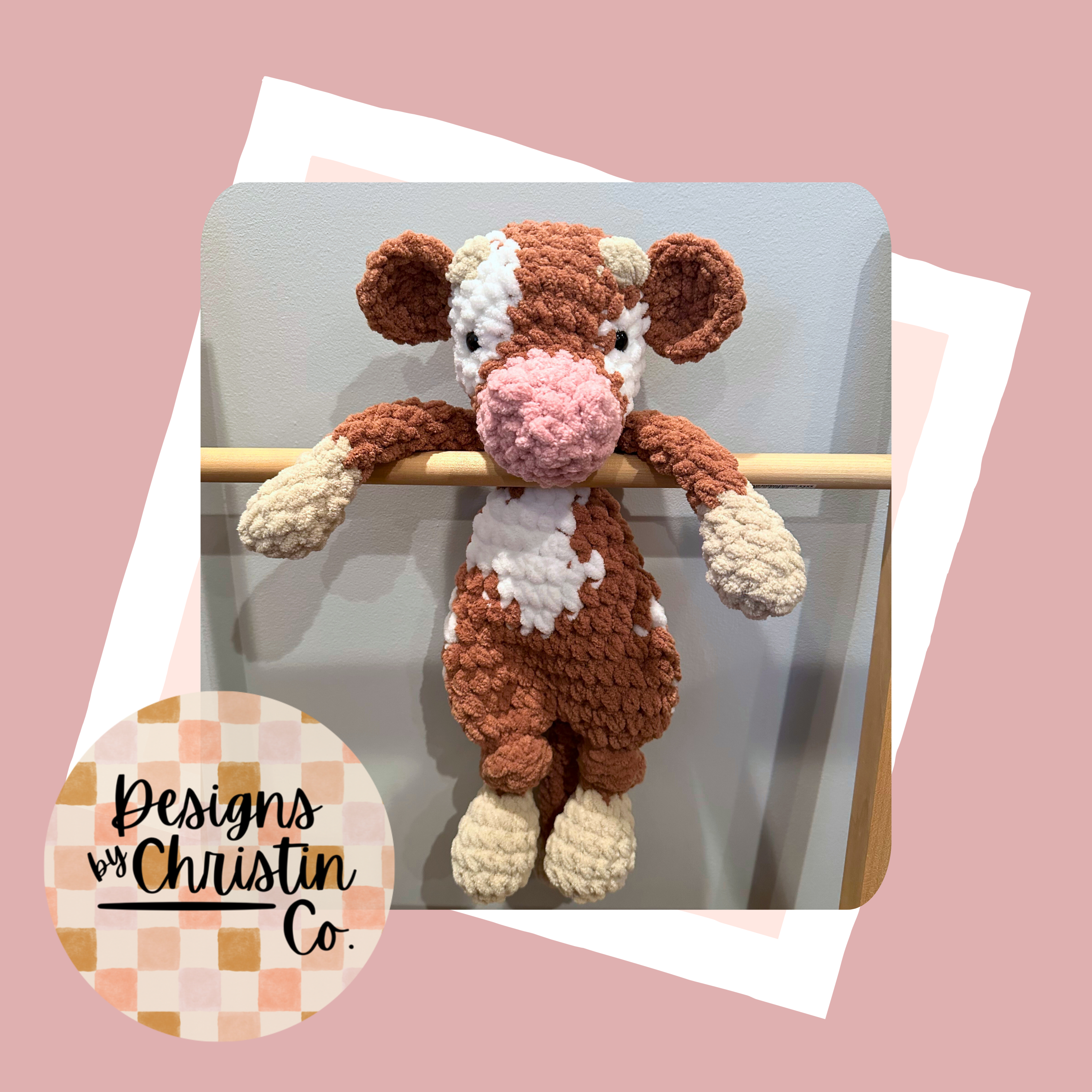 A crochet plush lovey resembling a cow with a brown and white color scheme.
