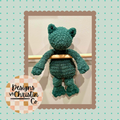 a crochet green frog plush lovey with a stuffed head and an unstuffed body.